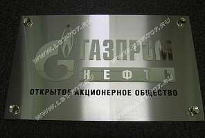 Объемная металлическая табличка ПАО «Газпром нефть» из шлифованной нержавейки с накладным зеркальным логотипом компании и эмалевой заливкой текста.